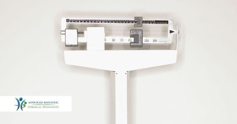 Doctor's office scale on gray background marks changing weight as a patient loses pounds after choosing bariatric surgery with Dr. Craig Chang