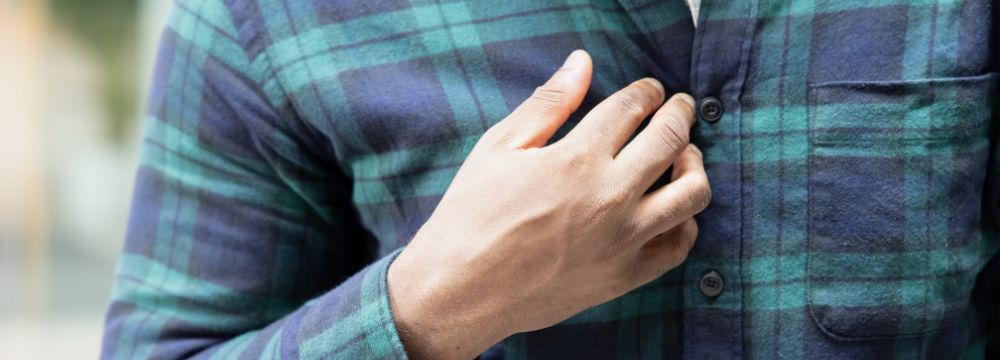 Man experiencing acid reflux putting hand to chest from pain 