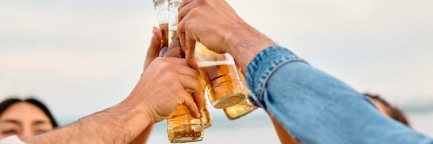 Four friends holding alcoholic drinks high together 