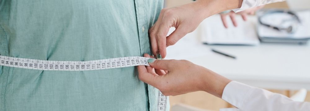 Provider using measuring tape to measure patient's waist size