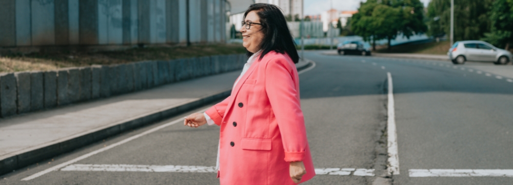 Woman, smiling, walking across street in crosswalk
