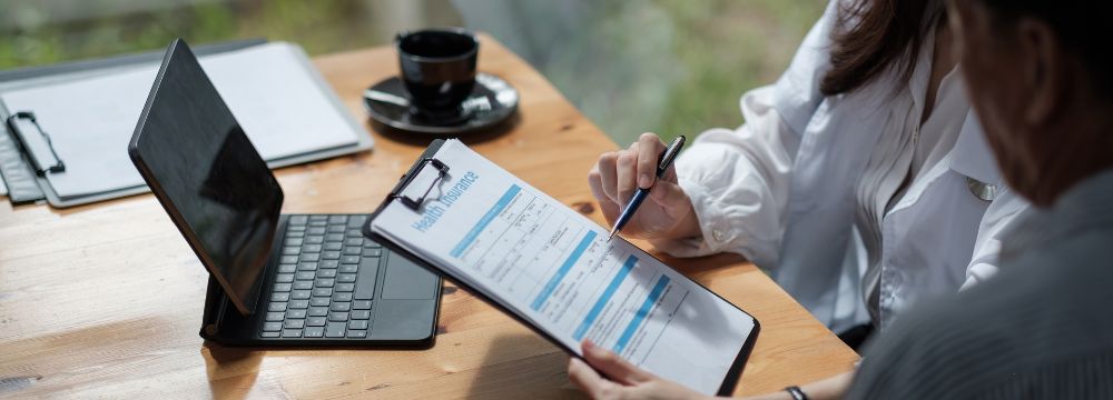 doctor and patient examining insurance policy at desk