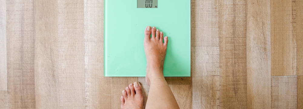 Woman stepping on bathroom scale with right foot 
