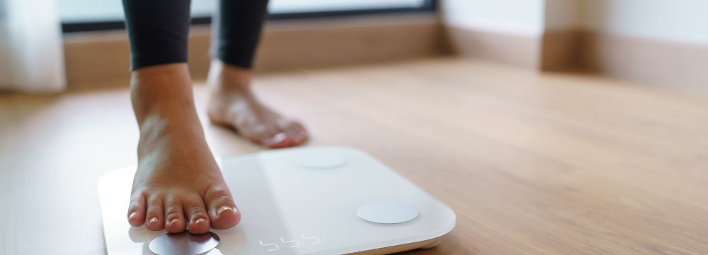 Right foot stepping on scale on wooden floor 