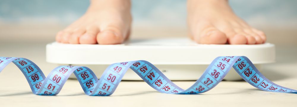 person standing on scale in background of coiled measuring tape