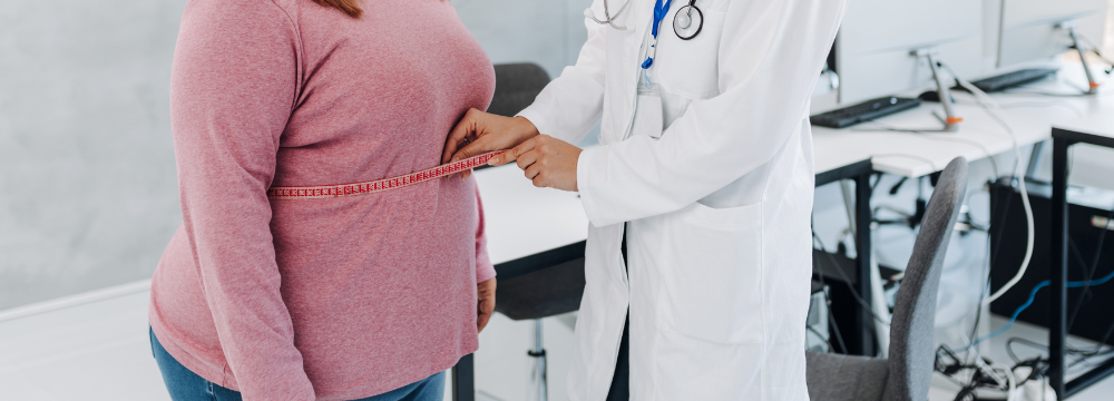 Woman at doctor's office getting waist measured by provider with measuring tape 