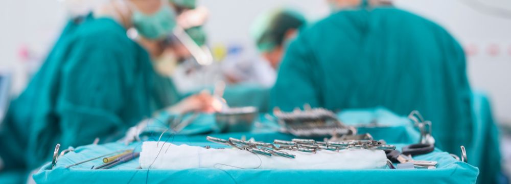 Surgeons in the operating room performing an operation next to tray of surgical tools 