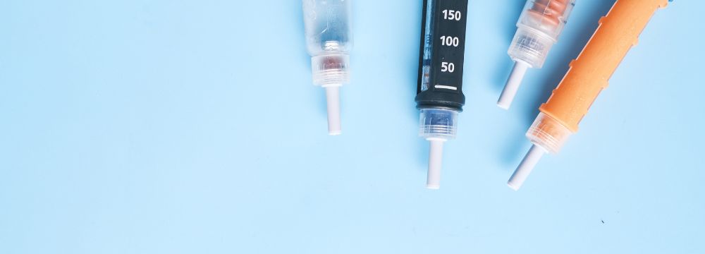 Diabetes injections scattered on blue backdrop